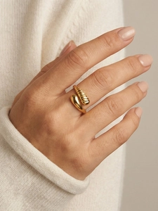 Close-up of golden tiered water drop ring featuring a spiral texture on an open band