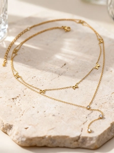 Vue détaillée du collier doré multicouche avec nœuds et zircons sur support en pierre