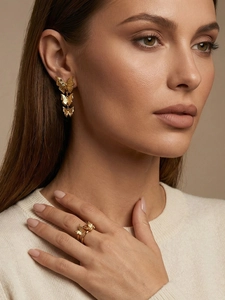 Close-up of golden butterfly long earrings and open ring with metallic texture