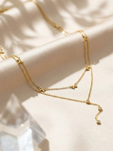 Détail du collier à double chaîne dorée avec nœuds et pampilles en zircon blanc
