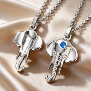 Polished stainless steel elephant pendant necklace with blue gemstone on silk background