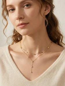 Détail du collier double rang doré avec nœuds et pendentif en cristal sur mannequin