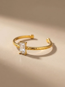 Detail of gold hammered ring band with marquise square zircon in a four-prong setting