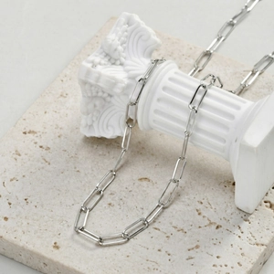 Detailed view of silver stainless steel paperclip chain on a white marble pillar stand