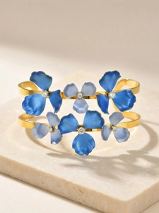 Detail of gold flower bangle featuring blue gradient petals and zircon centers on stone