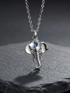 Detailed close-up of elephant pendant with blue stone on black textured stone surface
