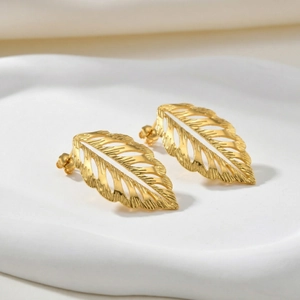 Chic hollow leaf stud earrings in gold-plated stainless steel on a white ceramic tray