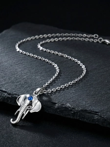 Macro detail of elephant pendant with blue gemstone on textured black background