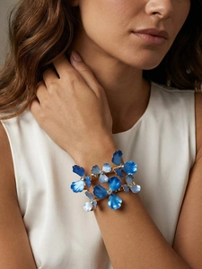 Detailed view of an elegant gold cuff bracelet featuring blue enamel flowers and crystals