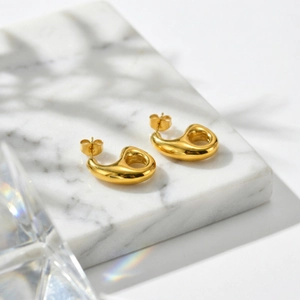 Gros plan de boucles d'oreilles dorées géométriques sur marbre avec reflets doux