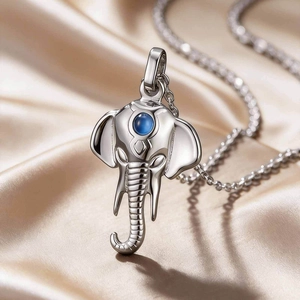 Detailed close-up of elephant pendant with blue gemstone on silver chain over silk