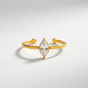 Detail of gold hammered metal ring with marquise cut zircon gemstone on white background