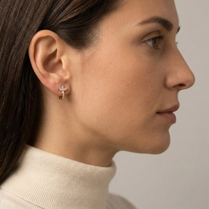 Close-up of gold earring with petal-shaped zircons worn by model in elegant style