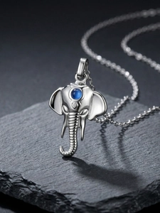 Detailed close-up of a silver elephant pendant with a round blue stone on a black stone