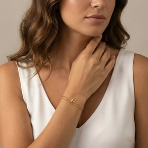 Bracciale a doppio strato dorato minimalista con croce, indossato sul polso per un look elegante