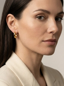 Gros plan d'un modèle portant des boucles d'oreilles créoles dorées au fini poli