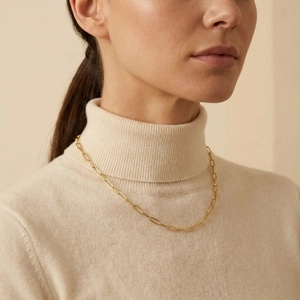 Elegant gold faceted paperclip chain necklace for women worn over a beige sweater