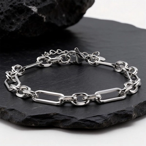 Polished silver stainless steel link bracelet with lobster clasp on dark stone surface