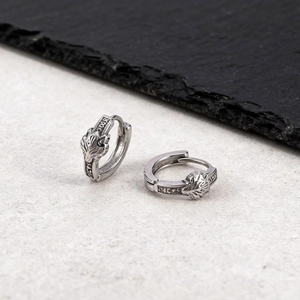 Detailed shot of silver viking wolf head earrings with runic engravings and retro finish