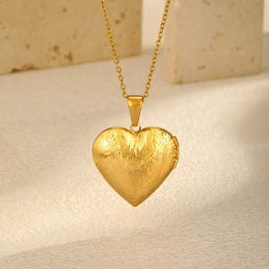 Detail of golden heart locket necklace with vintage floral engraving and openable design