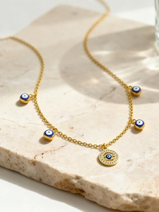 Détail du collier œil maléfique doré avec émail bleu et zircons sur fond de pierre