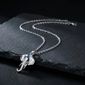 Polished stainless steel necklace with blue gemstone elephant pendant on black slate