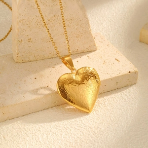 Detail of a vintage heart locket necklace with floral engraving on stone pedestal