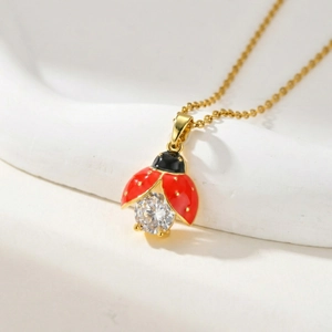 Collier pendentif coccinelle dorée avec émail rouge et pierre de zircon scintillante