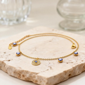 Gros plan d'une chevillère Evil Eye dorée avec pendentifs émaillés et zircons blancs