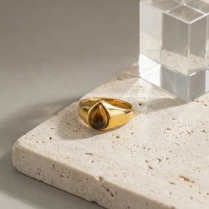 Détail d'une bague en acier doré sertie d'une pierre œil de tigre en forme de poire