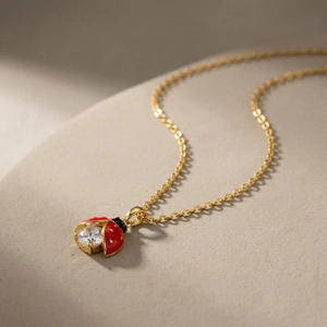 Macro d'un pendentif coccinelle doré avec émail rouge et détail en zircon scintillant