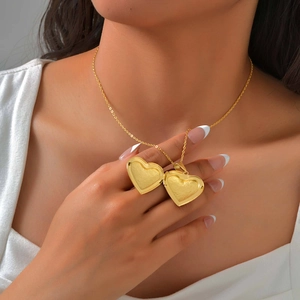 Detail of an open heart-shaped gold locket necklace with intricate floral engravings
