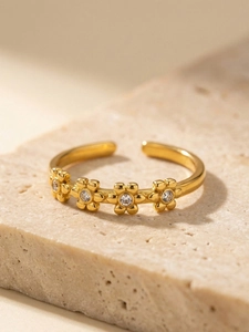 Close-up of golden adjustable flower ring featuring sparkling white cubic zirconia stones