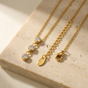 Détail du pendentif trois zircons sur chaîne dorée avec étiquette gravée K18 et fermoir