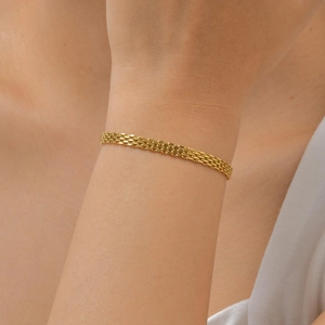Close-up of a gold mesh band bracelet worn on a woman wrist showing fine texture details