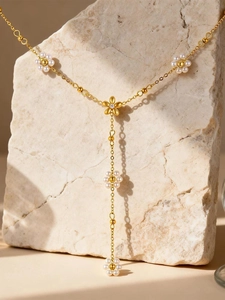 Dettaglio della collana a Y con fiori e perle dorate e piccoli diamanti su una pietra