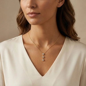 Gros plan d'un collier doré avec trois zircons verticaux porté par un mannequin