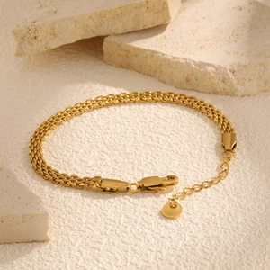 Detailed macro view of golden stainless steel mesh bracelet with lobster clasp and chain