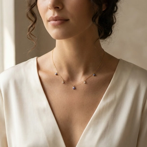 Détail du collier en chaîne dorée avec pendentifs œil bleu sur un mannequin féminin