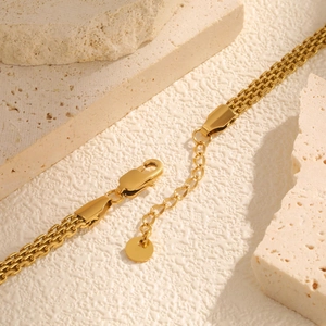 Detailed close-up of golden stainless steel mesh bracelet with lobster clasp and extension