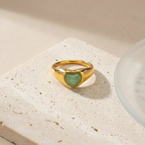 Détail d'une pierre d'aventurine verte en forme de cœur sertie sur une bague dorée