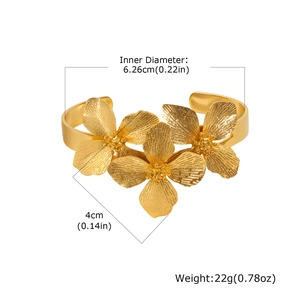 Gros plan d'un bracelet ouvert doré à motif floral avec pétales texturés et diamètre de 4 cm