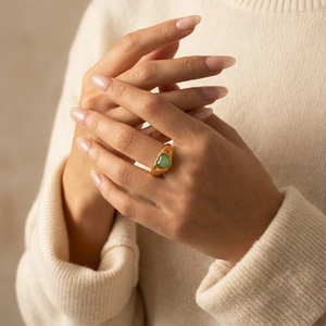 Gros plan d'une large bague en or 18 carats avec cœur en aventurine sur une main