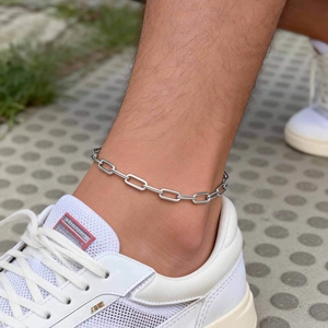 Detailed view of a silver minimalist rectangular link anklet worn on the ankle