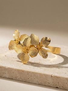Détail du bracelet fleur doré présentant des pétales texturés radiaux et un anneau fendu