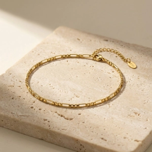 Detailed macro view of 18K gold Figaro chain with rectangle links and lobster clasp