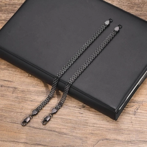 Detail of two black stainless steel mesh bracelets with lobster clasps on wood