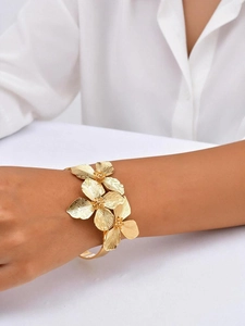 Détail d'un bracelet manchette ouvert fleuri doré avec texture en métal brossé