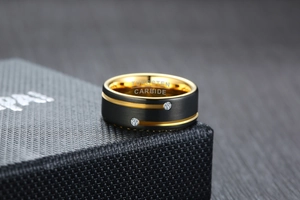 Macro shot of dual-tone tungsten carbide ring featuring matte black finish and gold inner band