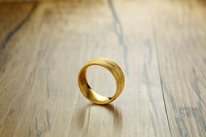 Macro shot of 8mm gold titanium ring featuring brushed sandblasted texture and polished edges
